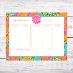 May include: A weekly planner with a bright blue background and a pattern of orange and pink fruit. The planner has sections for each day of the week, as well as a section for notes. The planner also has a monogrammed initial in the top right corner.