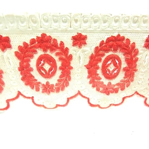 May include: White cotton lace trim with red embroidered floral designs. The trim features a scalloped edge and a repeating pattern of circles with diamond shapes inside.