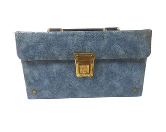 May include: A blue, textured, rectangular box with a brass latch and two brass rivets on the front. The box has a black handle.