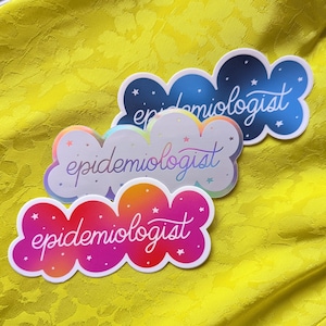 May include: Three iridescent stickers in the shape of a cloud with the text "epidemiologist" in white. The stickers are blue, white, and pink.