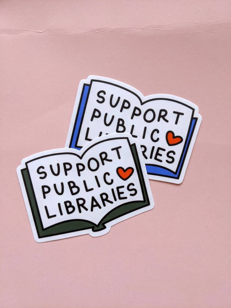 Pode incluir: Dois adesivos brancos em forma de livro com o texto "Support Public Libraries" e um cora&ccedil;&atilde;o vermelho. O adesivo de cima &eacute; azul e o adesivo de baixo &eacute; verde.