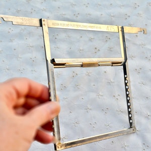 May include: A silver metal Kodak Filmland Plate Developing Hanger No. 43, marked 4/5, for photographic film.