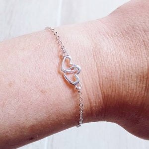 Peut inclure: Un bracelet en chaîne argent avec un pendentif en forme de double cœur.