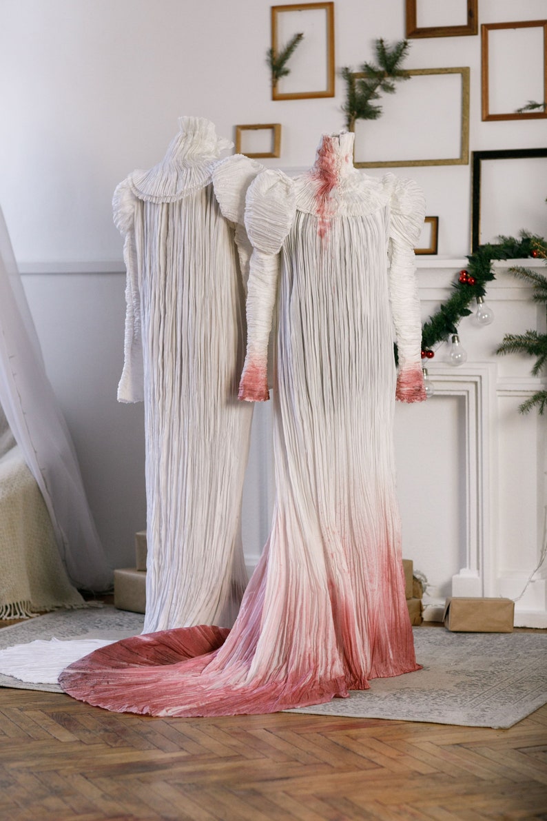 Puede incluir: Dos vestidos blancos con tela plisada. Un vestido es blanco liso, mientras que el otro tiene un efecto degradado rosa.
