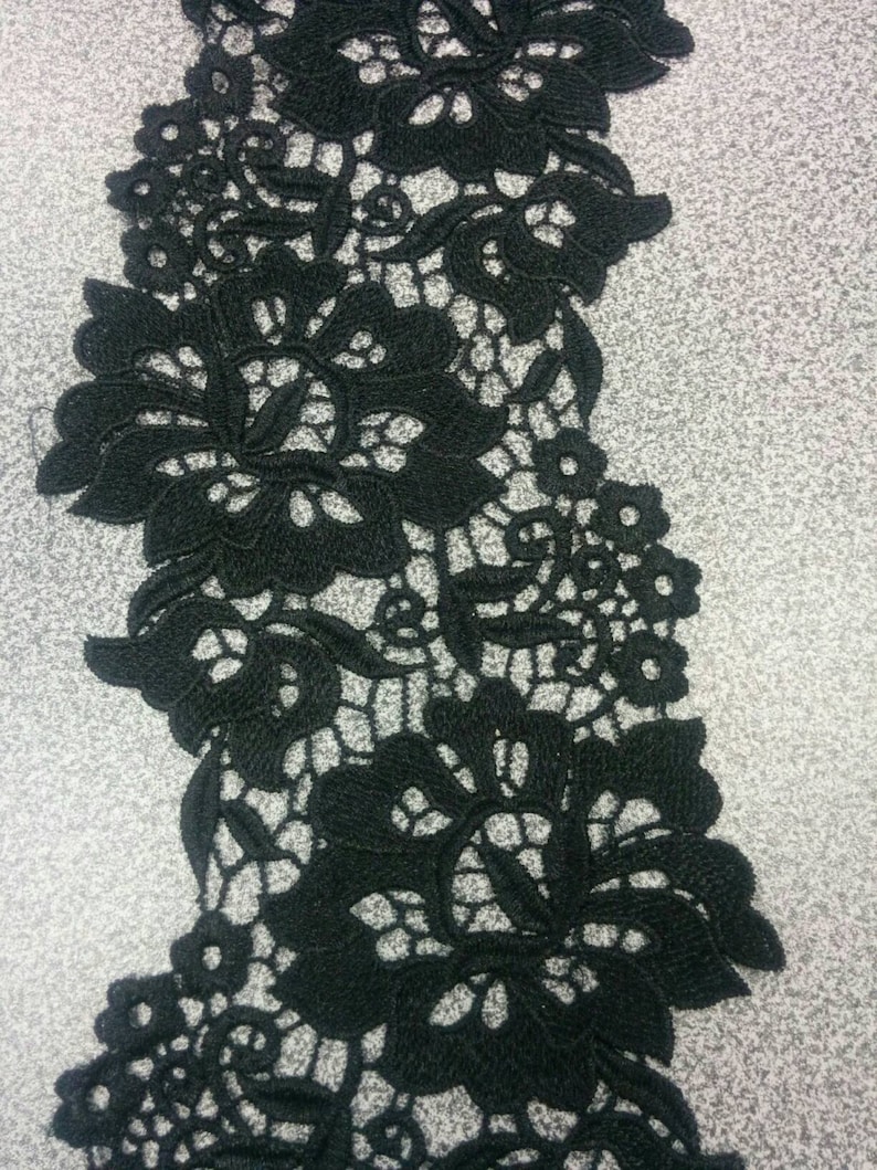May include: Black lace trim with a floral design. The lace is delicate and intricate, with a repeating pattern of flowers and leaves.