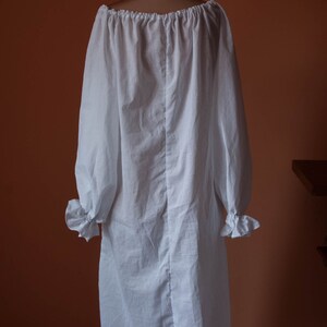 May include: A white, off-the-shoulder peasant blouse with long sleeves and a gathered neckline. The blouse is made of a lightweight fabric and has a relaxed fit.