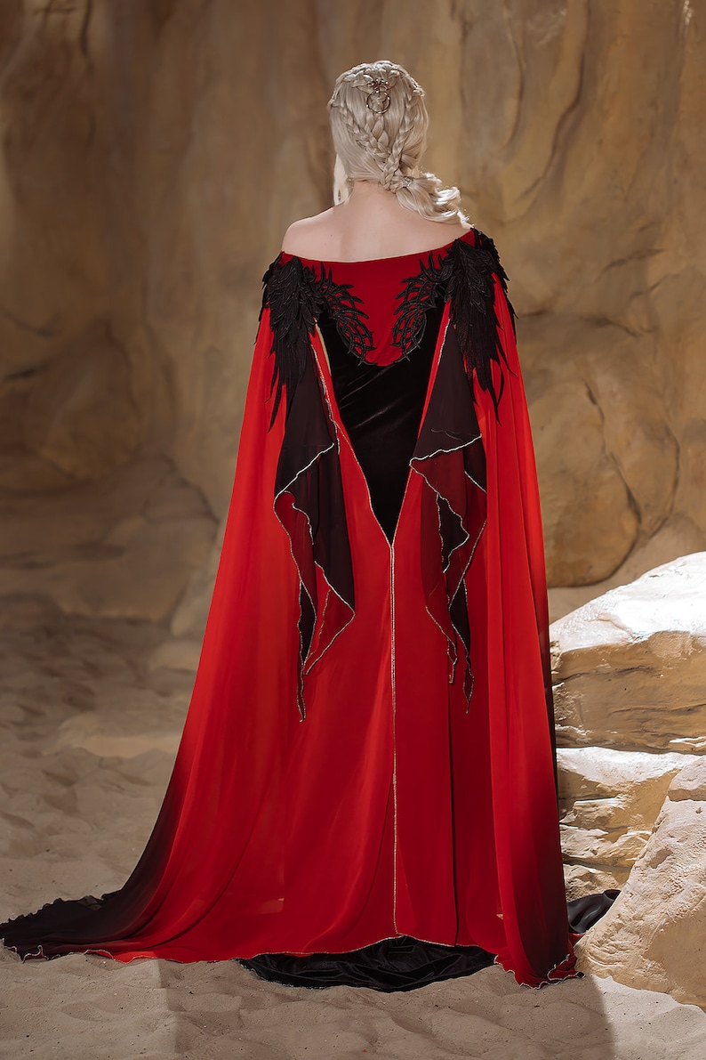 May include: A red and black cape with black lace detailing and a velvet bodice. The cape is flowing and has a long train.