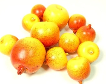 May include: A group of 10 yellow and orange fruit, some with a red blush, arranged on a white surface. The fruit are round and have a smooth texture.