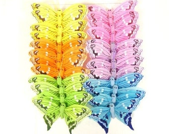 May include: Assortment of colorful butterfly craft supplies. The butterflies are made of fabric and have a layered, dimensional look. They are in shades of yellow, orange, green, blue, and pink.