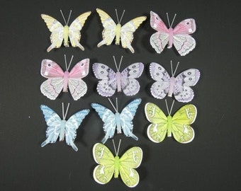 May include: Assortment of twelve colorful butterfly hair clips. The butterflies are made of fabric and have a wire antenna. The butterflies are in various colors, including pink, purple, blue, yellow, and green.