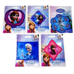 Może przedstawiać: Zestaw dziesięciu naszywek do prasowania z postaciami z filmu Disneya Frozen. Naszywki znajdują się na indywidualnych kartkach z logo Disneya Frozen i napisem "Iron-on Patches". Naszywki przedstawiają Annę, Elsę, Olafa i Kristoffera.