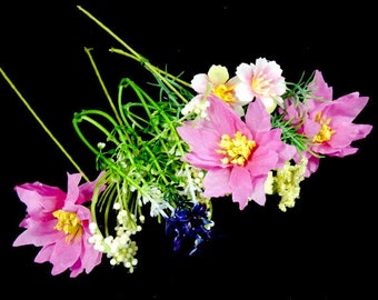 May include: A bouquet of pink, white, and yellow silk flowers with green stems and leaves. The flowers are arranged in a cluster and have a delicate, feminine appearance.