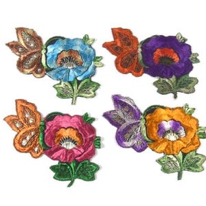 Puede incluir: Cuatro parches bordados para planchar con un diseño de mariposa y flor. Las flores son en tonos de azul, morado, rosa y naranja. Las mariposas son plateadas y doradas.