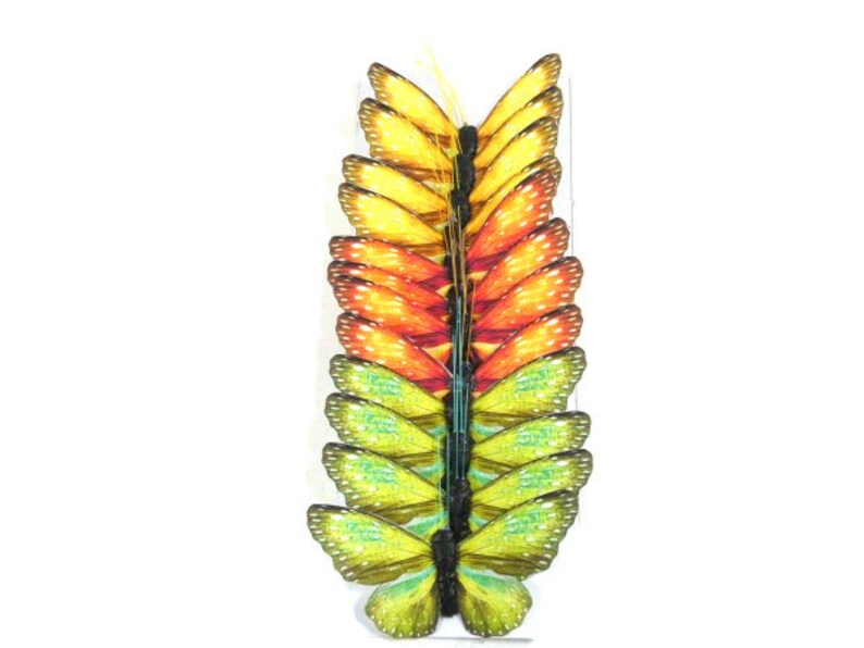 May include: A stack of 15 colorful paper butterflies in shades of yellow, orange, and green. The butterflies are arranged in a vertical stack, with the yellow butterflies at the top and the green butterflies at the bottom.