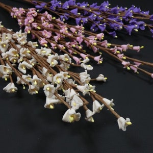 May include: Three bunches of artificial flowers with small bell-shaped blossoms. The flowers are white, pink, and purple.