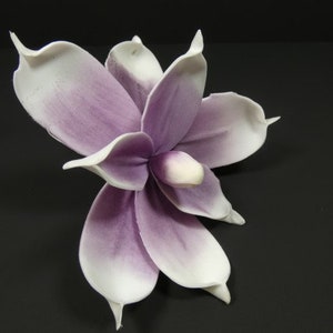 May include: A single artificial flower with white petals and a purple center. The flower is made of a soft, pliable material and has a realistic appearance.