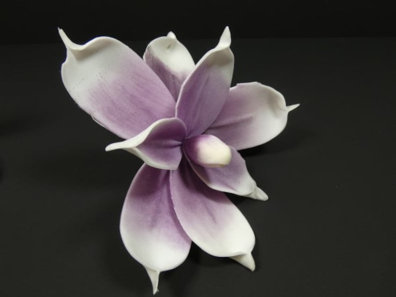 May include: A single artificial flower with white petals and a purple center. The flower is made of a soft, pliable material and has a realistic appearance.