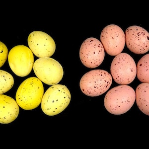 May include: Two groups of speckled Easter eggs, one group of nine pink eggs and one group of nine yellow eggs.