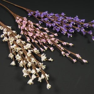 May include: Three sprigs of artificial flowers with small bell-shaped blooms. The flowers are white, pink, and purple.