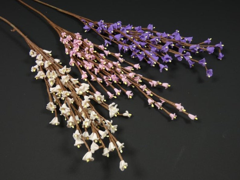 May include: Three sprigs of artificial flowers with small bell-shaped blooms. The flowers are white, pink, and purple.