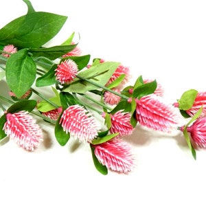 May include: A bunch of pink artificial clover flowers with green stems and leaves.
