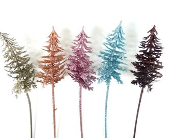 May include: Five artificial pine trees with glitter, in shades of brown, pink, copper, and blue.
