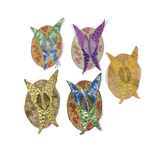 Puede incluir: Cinco parches bordados para planchar con forma de mariposa en varios colores, incluyendo morado, azul, verde y dorado. Cada parche es de forma ovalada y tiene un diseño floral.