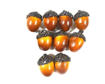 May include: Ten brown acorns with black tops, each acorn is covered in small black beads.