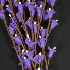 May include: A bunch of purple artificial flowers with brown stems. The flowers are small and bell-shaped.