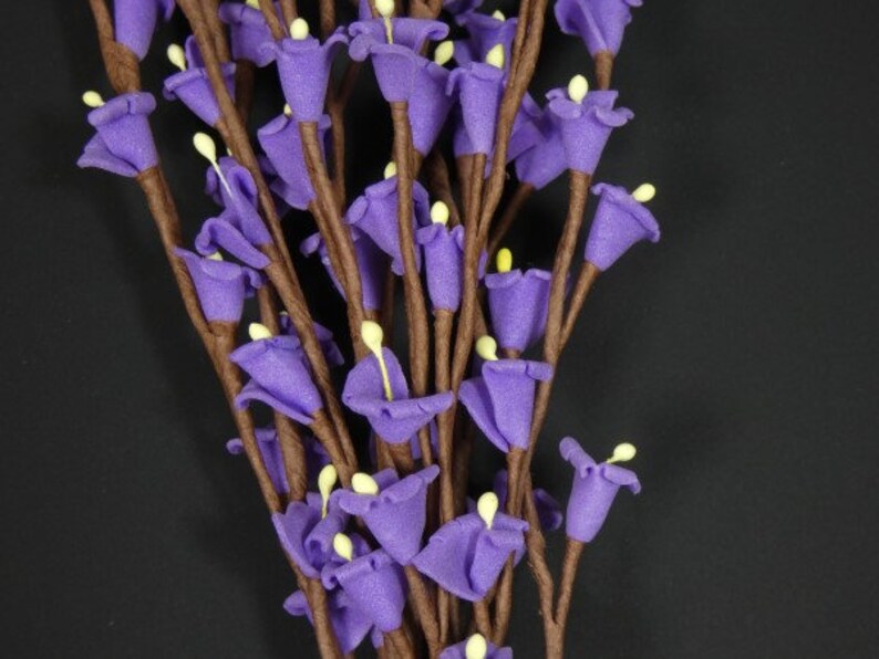 May include: A bunch of purple artificial flowers with brown stems. The flowers are small and bell-shaped.