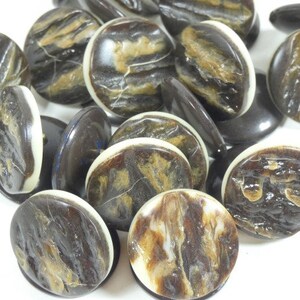 Op de afbeelding: Een verzameling bruine en witte gemarmerde knopen met een witte rand. De knopen zijn gemaakt van een natuurlijk materiaal met een unieke marmerlook.