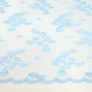 May include: Light blue lace fabric with a delicate floral pattern. The lace has a scalloped edge.