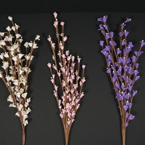 May include: Three bunches of artificial flowers with small bell-shaped blooms. The flowers are white, pink, and purple.