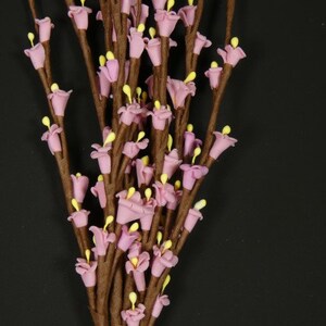 May include: A bunch of artificial flower stems with small pink flowers and brown stems.