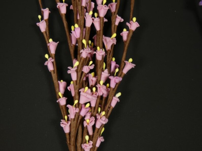 May include: A bunch of artificial flower stems with small pink flowers and brown stems.