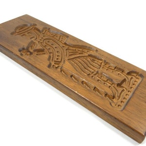 Pu&ograve; includere: Uno stampo per biscotti in legno con una scultura dettagliata di una persona in costume tradizionale. Lo stampo &egrave; in legno marrone scuro e ha una finitura liscia e lucida.