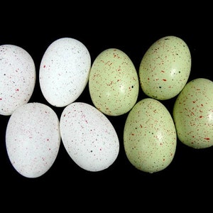 May include: Eight speckled Easter eggs in a variety of green and white colours. The eggs are arranged in a circle on a black background.