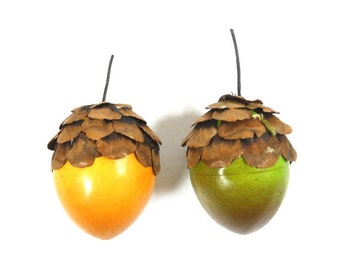 May include: Two acorn ornaments, one is orange and the other is green. Both have a brown cap made of natural materials.