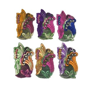 Puede incluir: Seis parches bordados para planchar con un diseño de mariposa con detalles florales. Los parches son de varios colores, incluyendo morado, rosa, naranja y verde.