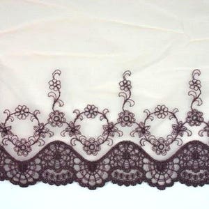 May include: Brown lace trim with a scalloped edge and floral embroidery. The lace is delicate and intricate, with a subtle sheen.