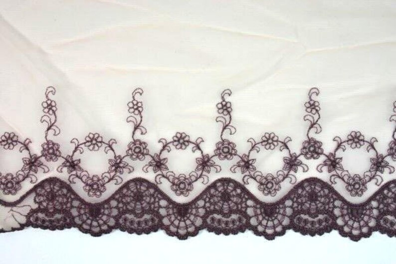 May include: Brown lace trim with a scalloped edge and floral embroidery. The lace is delicate and intricate, with a subtle sheen.