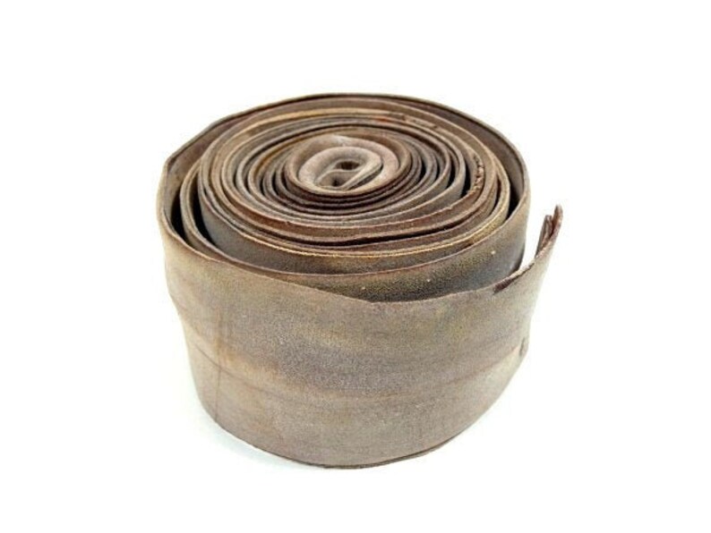 May include: A roll of brown leather, tightly wound and tied with a string. The leather is a light brown color and has a slightly textured surface.
