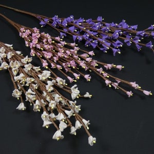 May include: Three artificial flower stems with small bell-shaped flowers. The stems are brown and the flowers are white, pink, and purple.