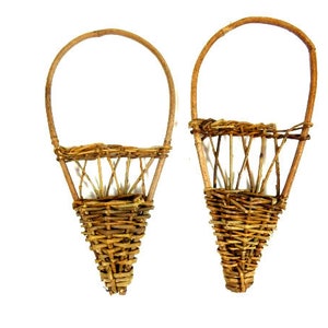 Peut inclure: Deux paniers en osier brun avec un dessus arrondi et un fond pointu. Les paniers sont faits de brindilles tissées et ont un aspect rustique.
