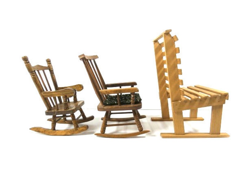 Puede incluir: Tres sillas de madera, dos mecedoras y un banco. Las mecedoras son de madera oscura y tienen respaldo y asiento de listones. El banco es de madera m&aacute;s clara y tiene respaldo y asiento de listones.