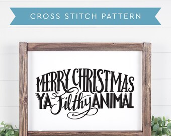 May include: A framed cross stitch pattern with the text "Merry Christmas Ya Filthy Animal" in black lettering on a white background.