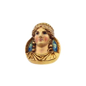 May include: A gold-toned brooch featuring a detailed portrait of a woman with a crown, set against a blue and white enamel background.