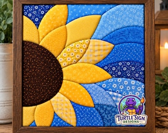 May include: A square fabric wall art piece in a dark wood frame featuring a quilted sunflower design. The sunflower has a dark brown center and yellow petals with various patterns. The background consists of layered blue fabric waves.