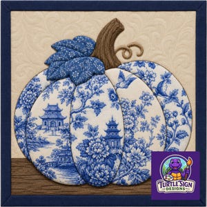 May include: A square fabric wall hanging featuring a quilted pumpkin with blue and white chinoiserie patterns on a cream background. The pumpkin has a brown stem and blue floral leaves, framed by a dark blue border with a Turtle Sign Designs logo.