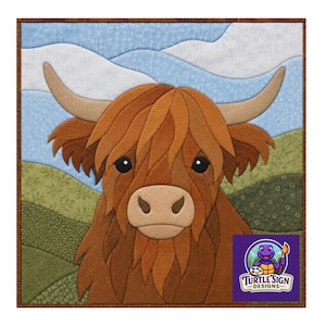 May include: A fabric wall hanging featuring a Highland cow with long brown fur, curved horns, and a tan muzzle. The background displays rolling green hills and a light blue sky with white clouds. A purple logo with a turtle and text reads Turtle Sign Designs.